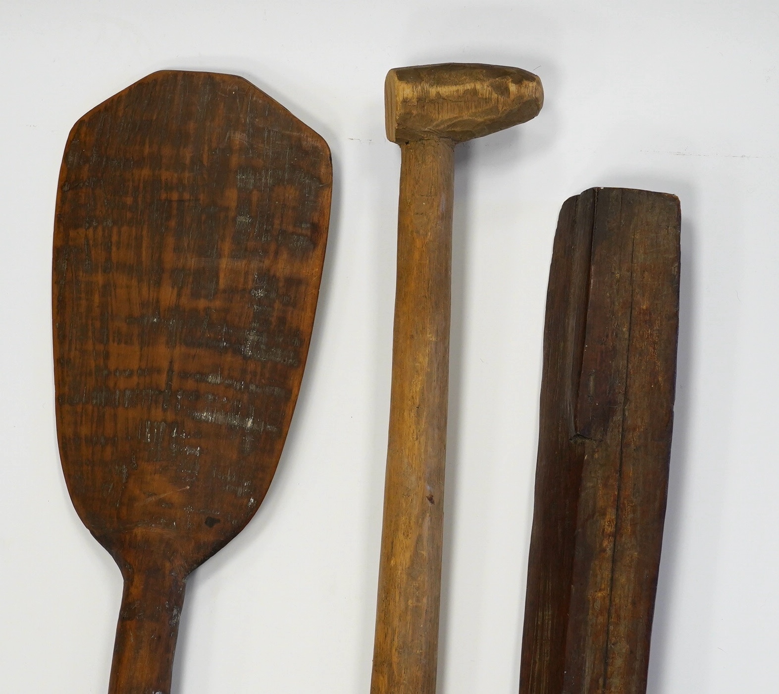 Two tribal carved wood paddles and an ironwood club, longest 104cm. Condition - poor to fair, one paddle missing part of the grip, splits to the wood, etc.